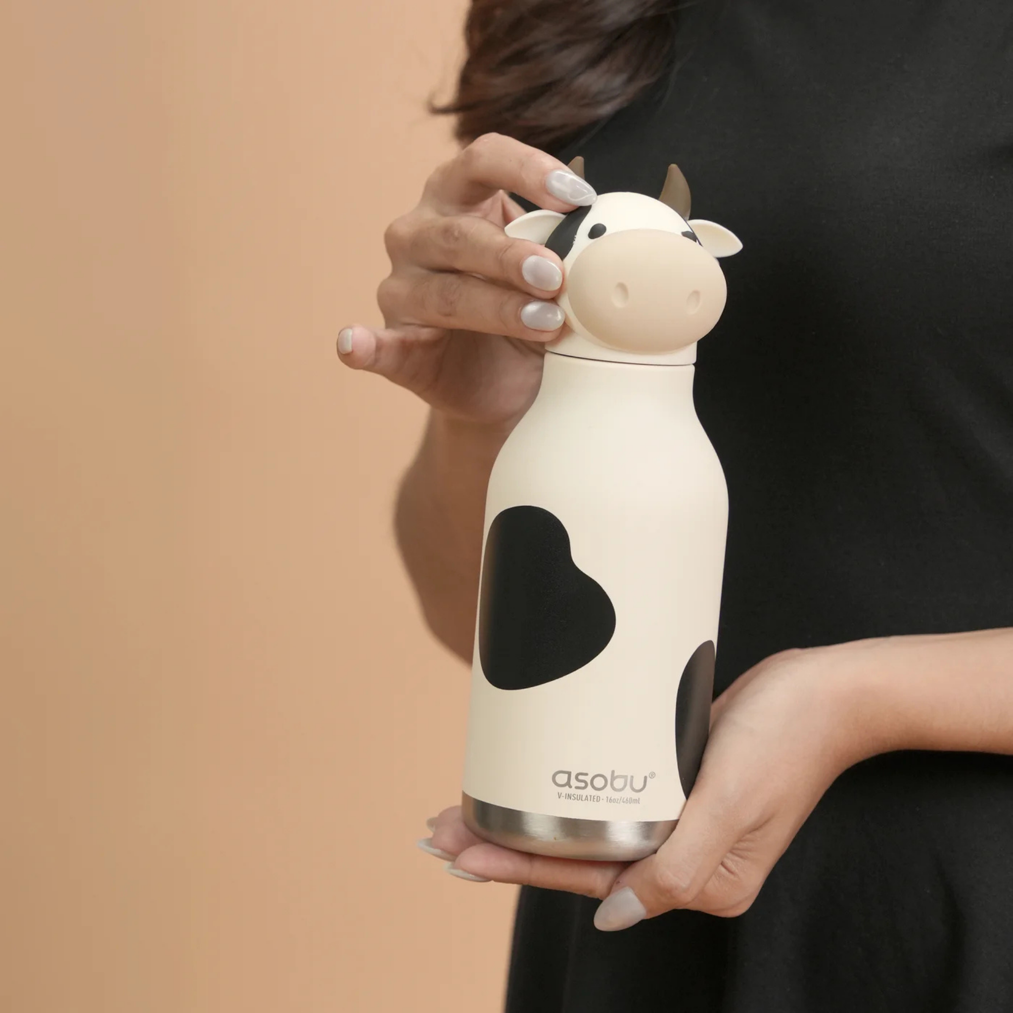 Child carrying Asobu Animal Bestie Bottle in Cow design with removable silicone character head during an everyday adventure in Whistler