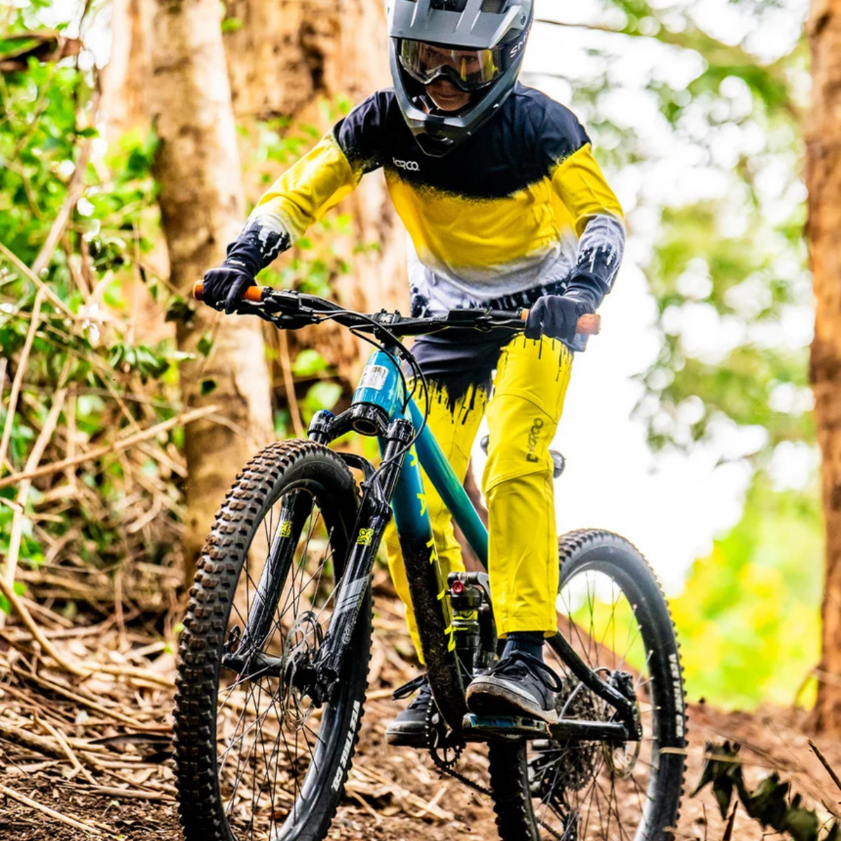 Young mountain biker wearing DHaRCO Youth Gravity Pants with water-resistant 4-way stretch fabric and knee pads in Whistler