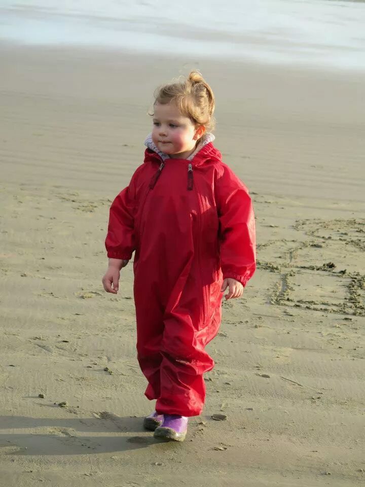 Little girl walking in the sand wearing Red Tuffo Muddy Buddy Mountain Kids Canada rain suit.