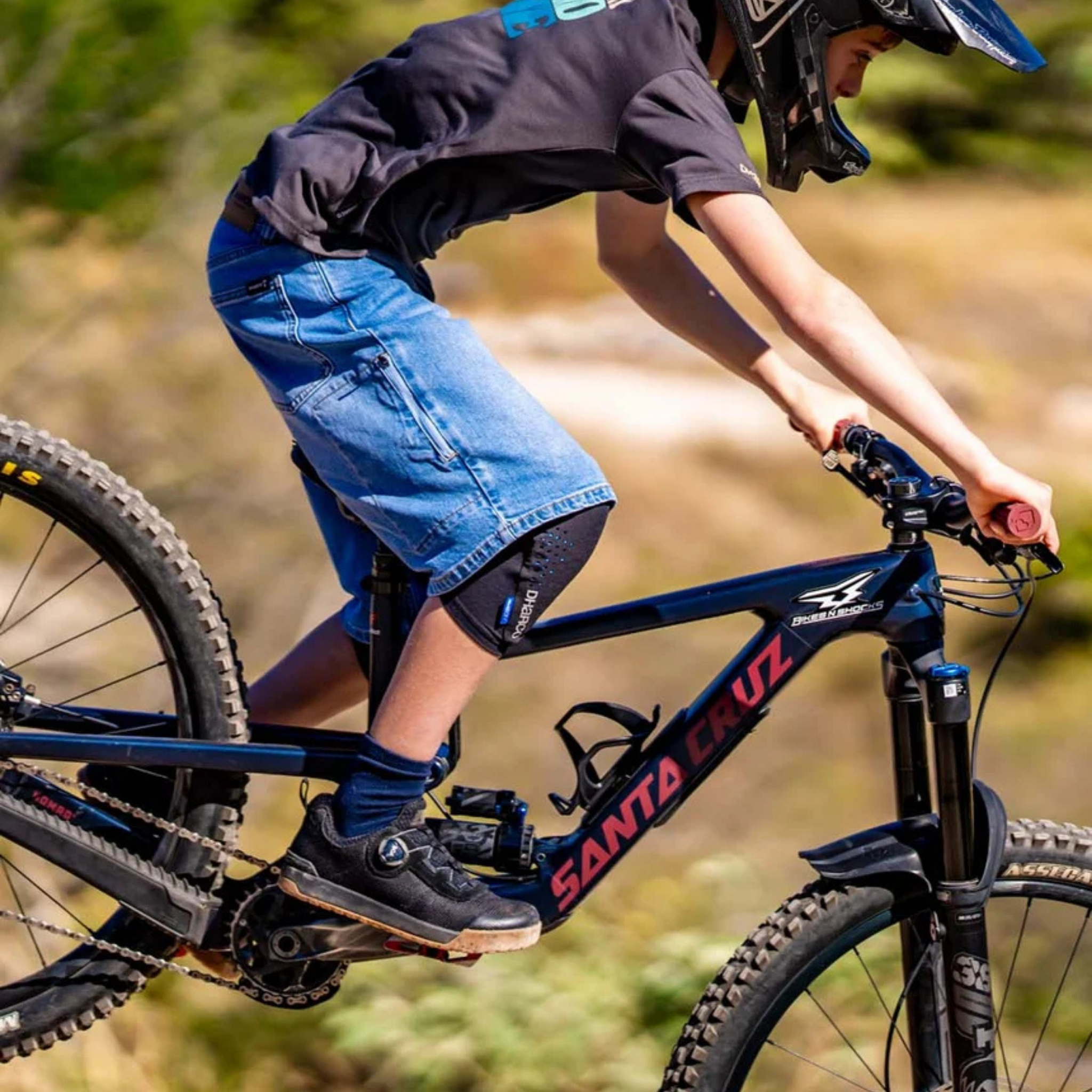 Young mountain biker wearing DHaRCO Youth Trail Knee Pads with CE-certified RHEON protection while trail riding in Whistler