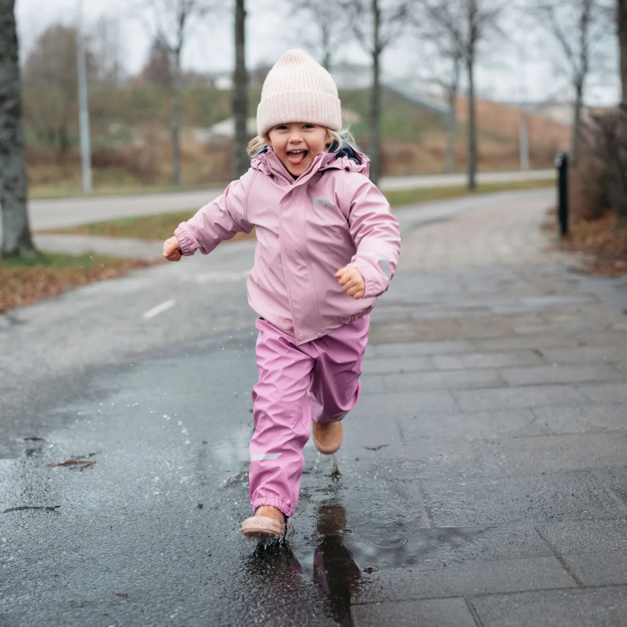 Child wearing Helly Hansen Kids Bergen 2.0 Rain Set with waterproof jacket and bib overalls on a rainy day in Whistler
