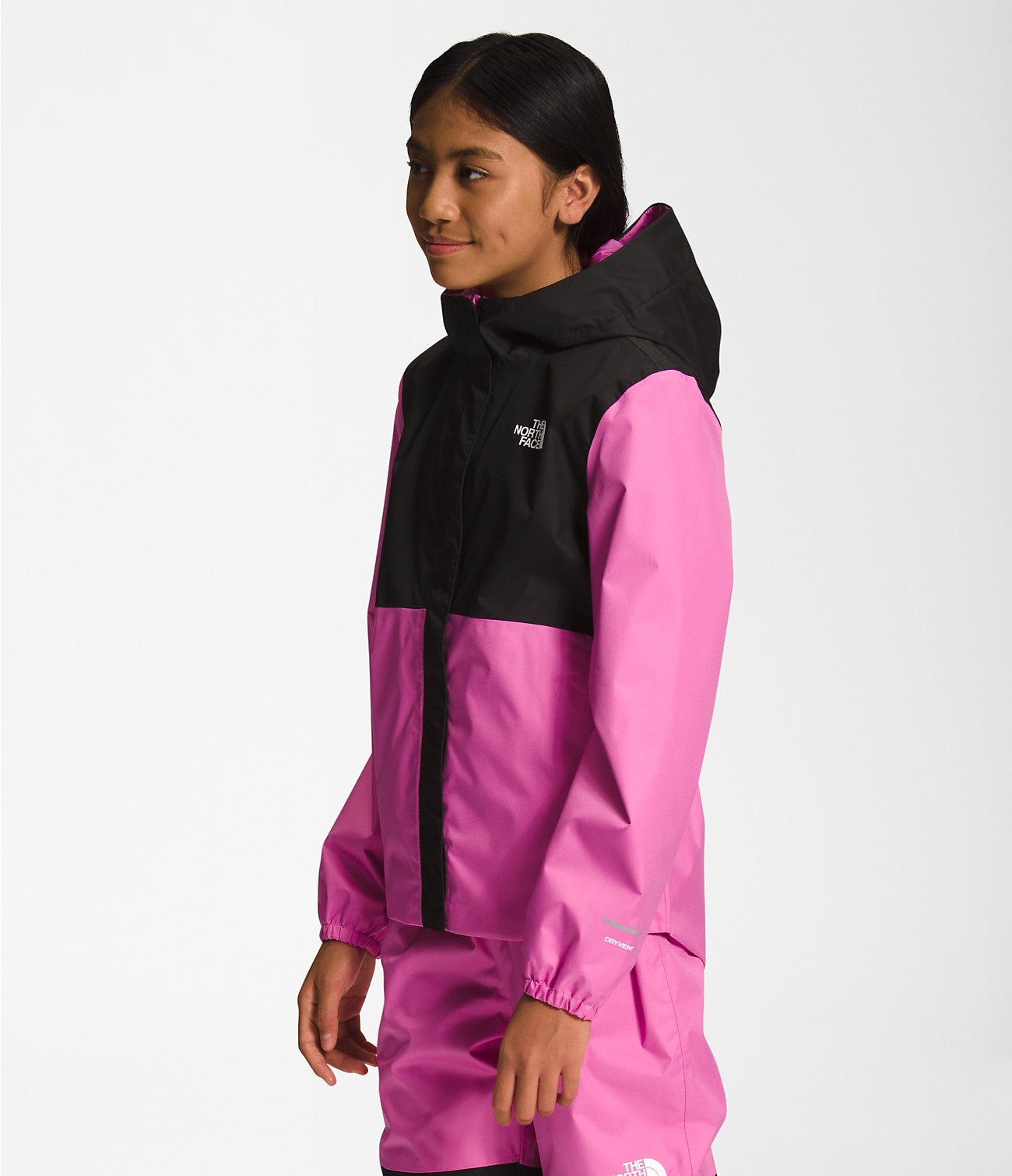 Side view of a Smiling girl wearing Super Pink The North Face Girls' Warm Storm Jacket - Mountain Kids Outfitters: Stylish and Weather-Ready Outerwear