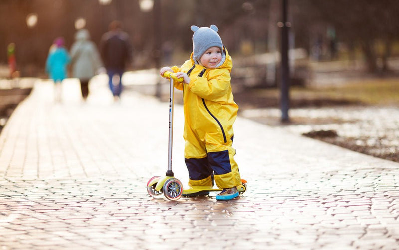 Smiling little boy wearing Yellow Tuffo Muddy Buddy Mountain Kids Canada rain suit, enjoying skating in the park.
